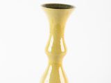 a yellow vase that is sitting on a white surface