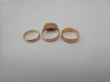 three gold rings sitting on top of a white surface