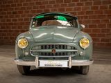 a green car that is parked in front of a brick wall