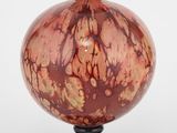 un vase orange et noir posé sur un socle noir