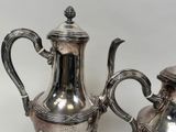two silver teapots sitting next to each other on a table