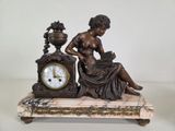 a statue of a woman sitting on a table with a clock