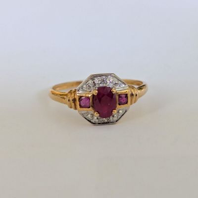 gros plan d'une bague en or avec un rubis et des diamants