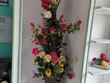 a tall vase with flowers in it in the corner of a room
