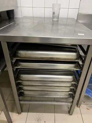 une table en acier inoxydable sur laquelle sont posés quatre bacs