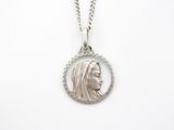 a close up of a silver necklace with a woman ' s face in a circle