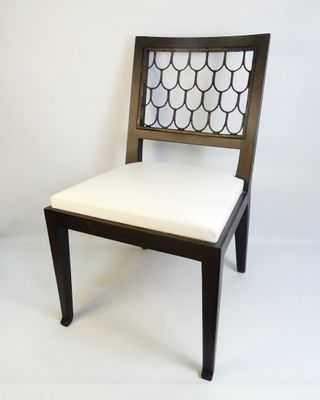 the back of a wooden chair with a white cushion on it
