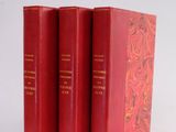 three red books sitting on top of each other on a white surface