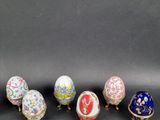 six different colored eggs sitting in a row on a black surface