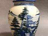 a blue and white vase with a mountain scene on it