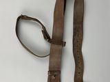 une vieille ceinture en cuir marron avec une boucle en métal sur un fond blanc