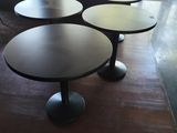 trois tables rondes sont disposées devant une grande fenêtre dans une pièce