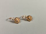 une paire de boucles d'oreilles en or ornées de perles, posée sur une table
