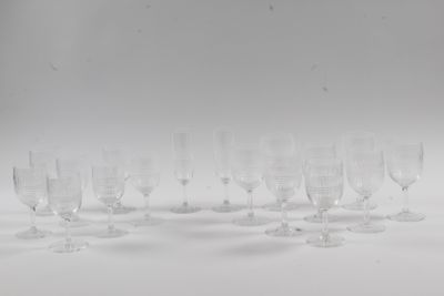 six clear wine glasses are lined up on a white surface