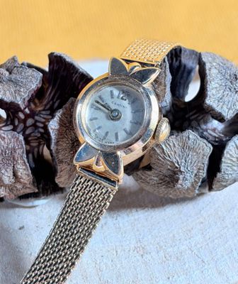 a silver watch sitting on top of a silver bracelet