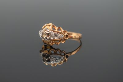 un gros plan d'une bague en or sertie de diamants sur une surface réfléchissante