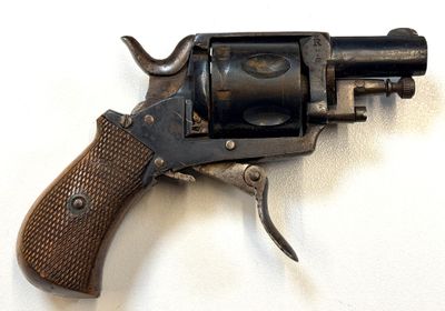 un vieux pistolet avec une poignée en bois sur une surface blanche