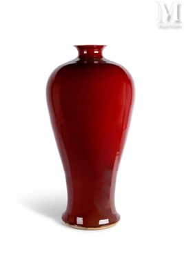 un vase rouge posé sur une surface blanche