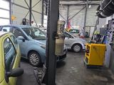 une voiture jaune garée dans un garage, avec d'autres voitures en arrière-plan