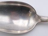 a silver spoon with a handle on a white surface