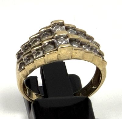 une photo d'une bague en or et diamants posée sur un socle noir