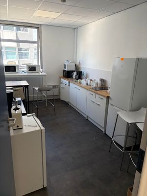 une photo d'une cuisine avec un réfrigérateur, un micro-ondes et une table