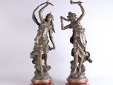 paire de statues en bronze représentant une femme et un oiseau, posées sur un socle en marbre