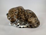 a figurine of a leopard laying down on a white surface