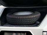 a tire in the trunk of a car with it ' s hood open