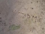 an old silver plate with writing on it sitting on the ground