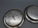 pair of silverplated plates with raised rims on a table