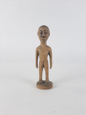 an old wooden figurine of a man standing on a white surface