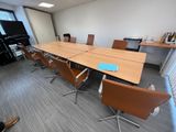 des tables et des chaises dans une salle de réunion équipée d'un grand écran