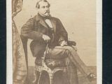 portrait d'un homme assis sur une chaise, une canne à la main