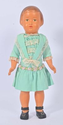 une poupée qui porte une robe verte et des chaussures noires