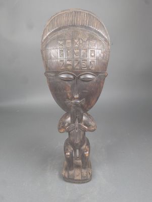une vieille statue en bois d'un homme avec un chapeau sur la tête