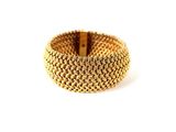 gros plan d'un bracelet en or sur fond blanc