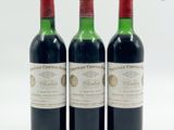trois bouteilles de vin rouge posées l'une à côté de l'autre sur une surface blanche