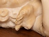 a statue of a baby laying down on a wooden table