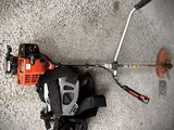 a close up of a string trimmer on the ground next to a pair of gloves and a pair of scissors