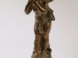 an antique bronze statue of a boy playing a flute
