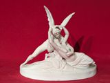 statue représentant une femme agenouillée sur un homme ailé, sur fond rouge