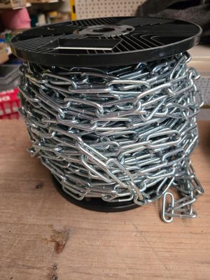 une bobine de chaîne posée sur une table à côté d'une paire de ciseaux