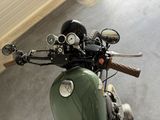 a green motorcycle parked in a garage with a mirror on the handlebar