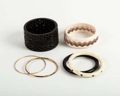 three different rings and bracelets sitting on top of a white surface