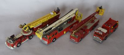 several toy fire trucks are lined up on a white surface