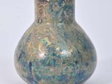 un vase bleu et vert posé sur une surface blanche