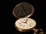 a gold pocket watch sitting on a black surface