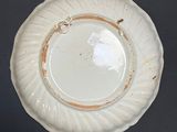 a white plate with a gold rim on a black table