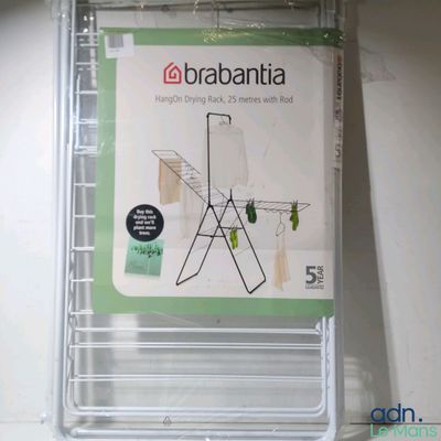 une boîte contenant un séchoir à linge « Brabantita » sur lequel sont suspendus des vêtements